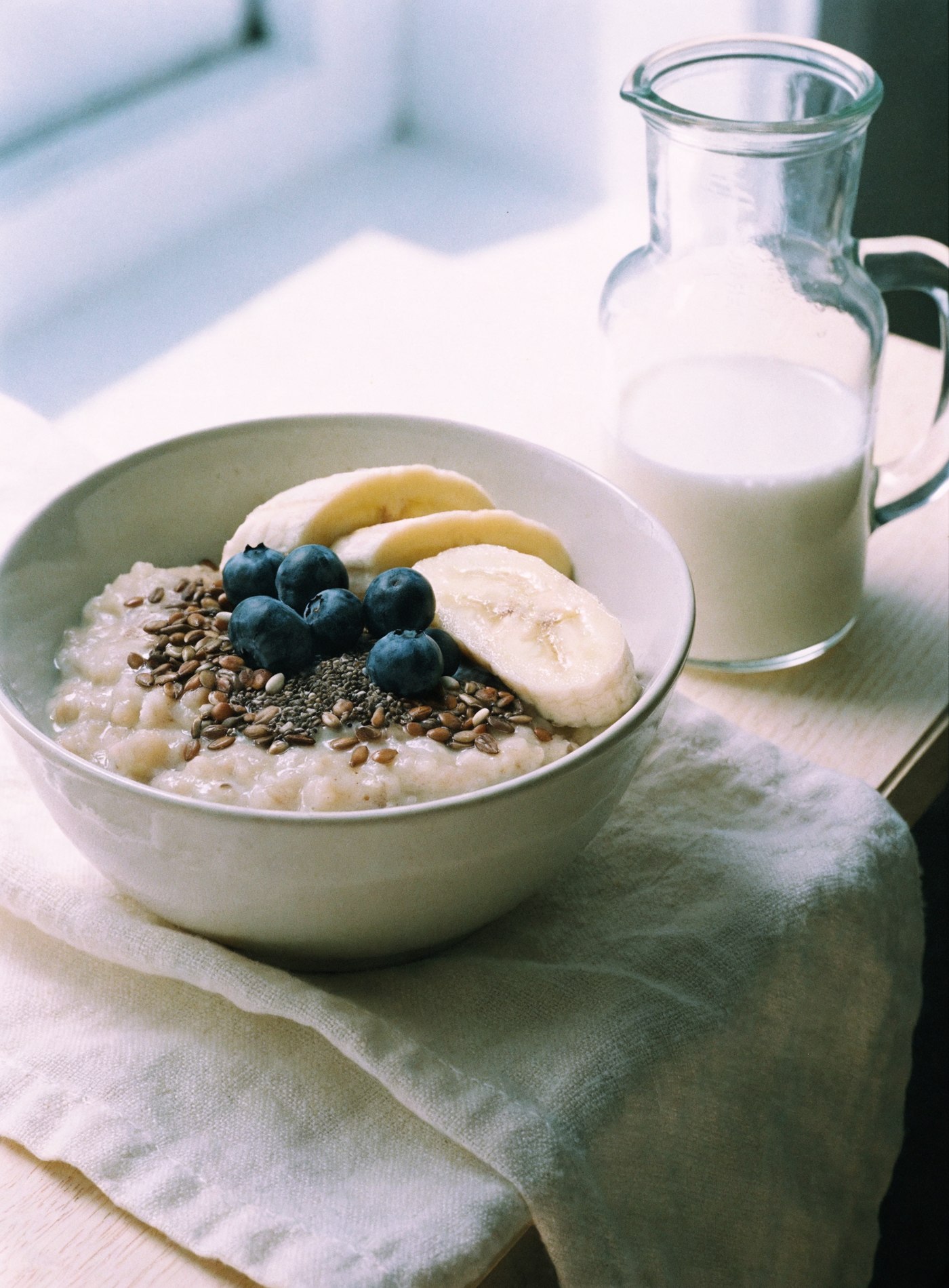 Porridge with banana, blueberries and seeds on cream linen