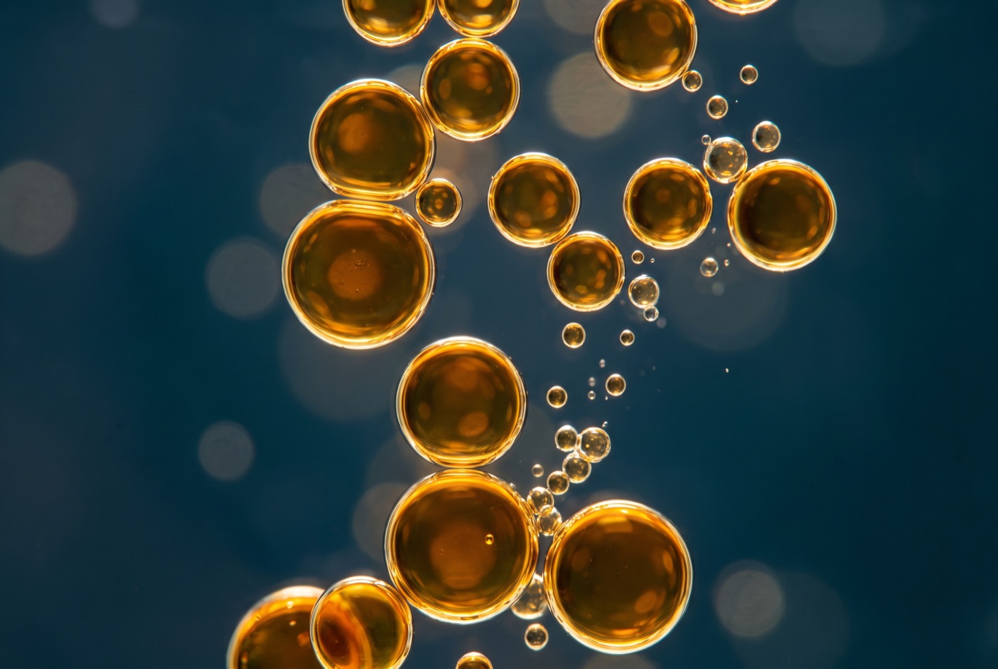 Golden oil droplets dispersing in water
