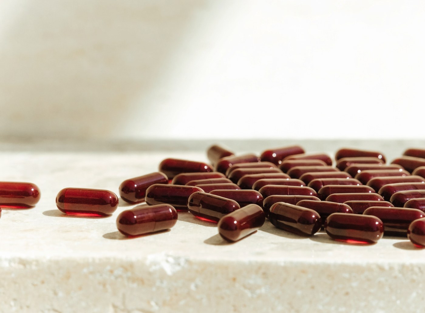 Dark red resveratrol capsules beside a plain cream jar